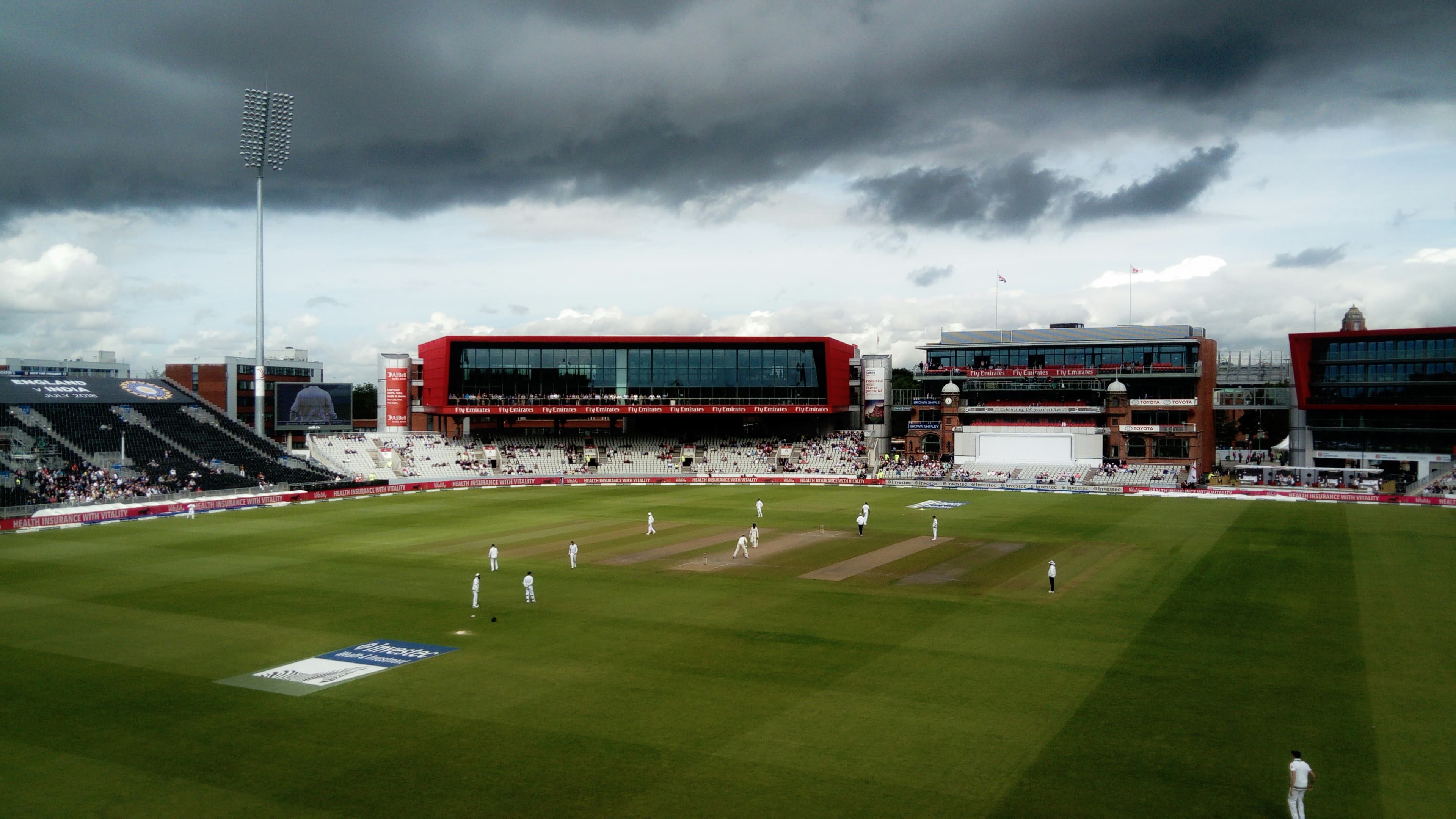 a cricket field with a cloudy sky in the background